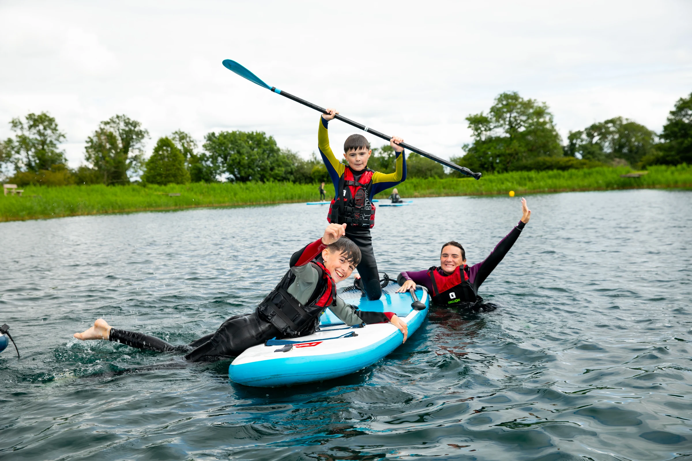 Young participants smiling and raising a paddle together at Moira Lakes